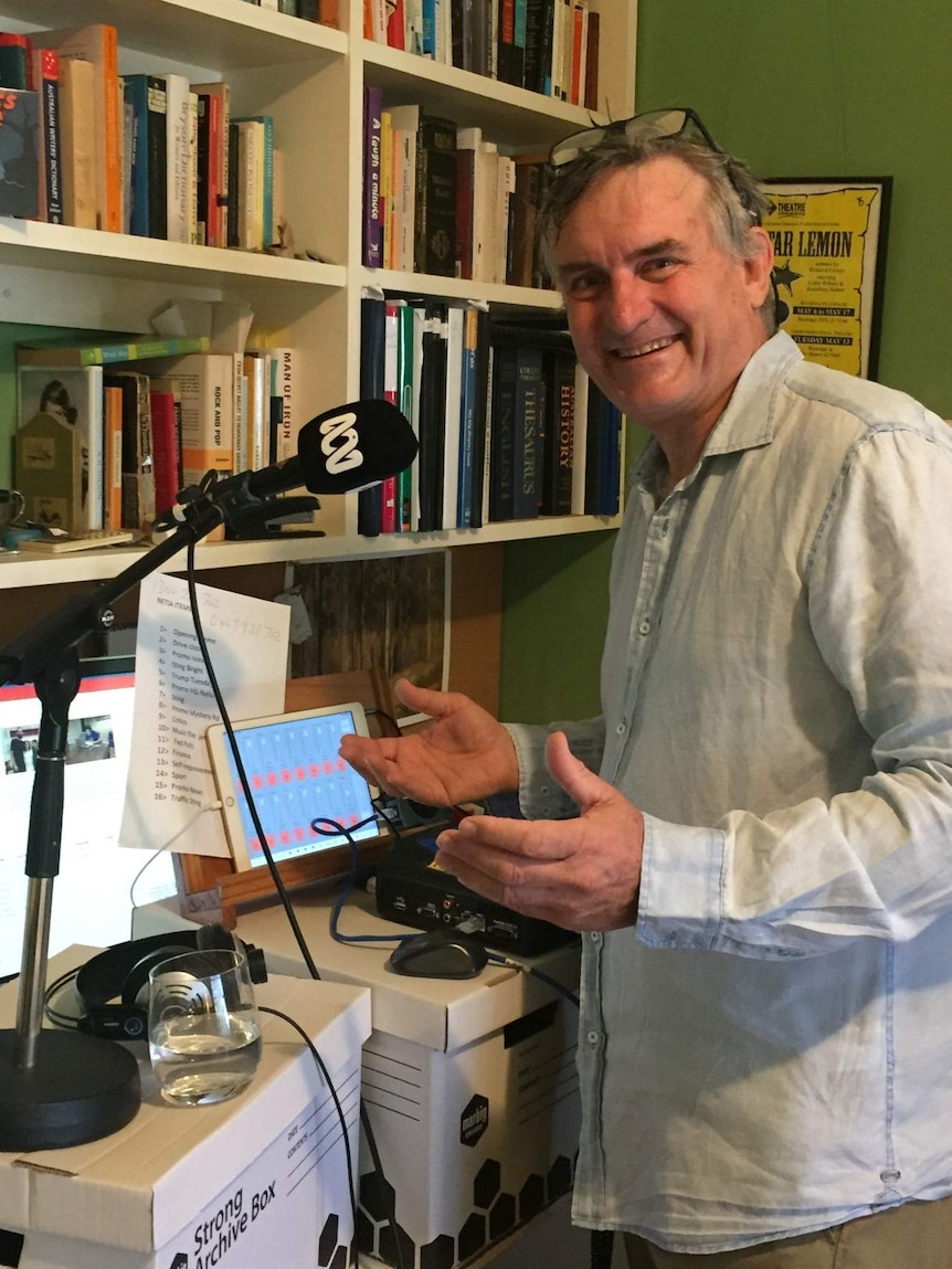 Glover standing at desk in front of ABC microphone.