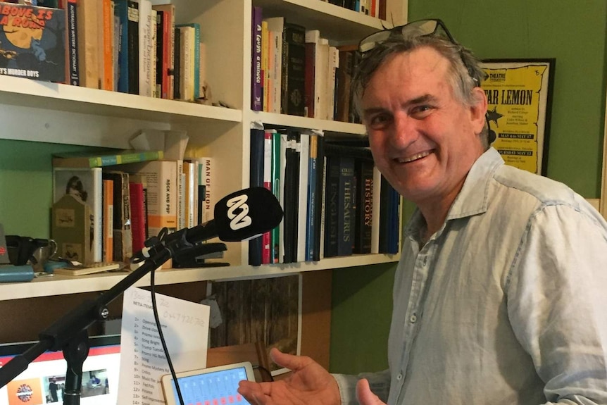 Glover standing at desk in front of ABC microphone.