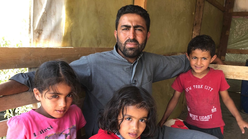 Refugee Ahmad with his three children at a refugee camp