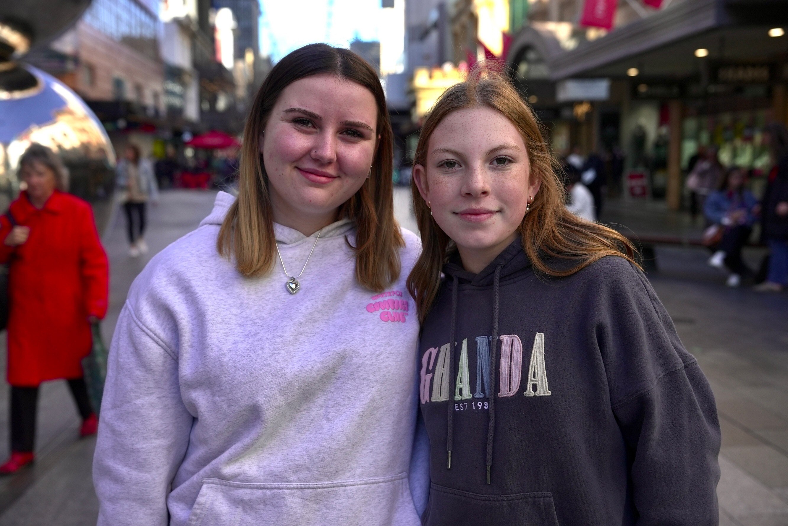 Two teenage girls stand together smiling.
