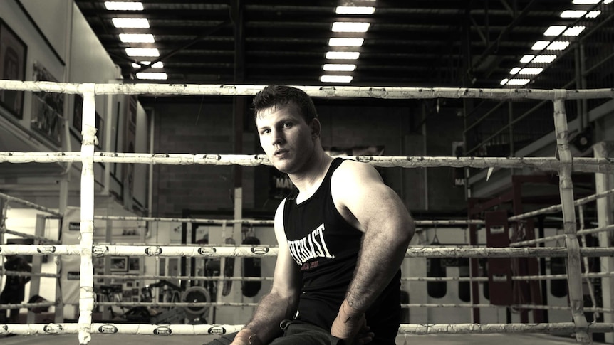 Black and white image of boxer sitting on box ringside