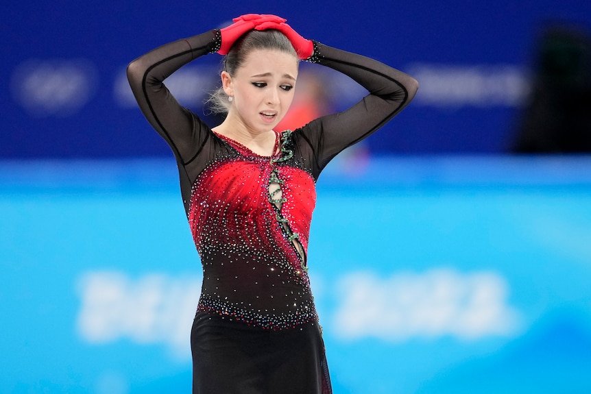 Kamila Valieva holds her hands on her head and appears stressed while looking down