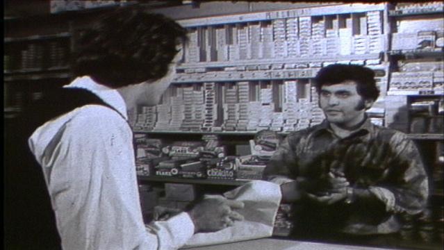 Man speaks to shopkeeper in shop