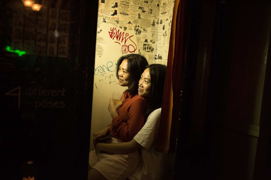 two women hugging and smiling in a photo booth