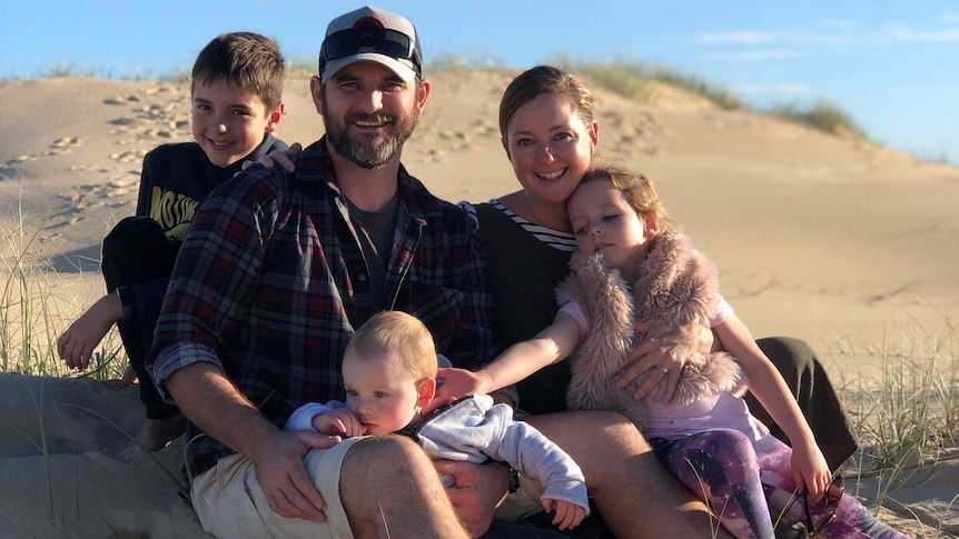 Chontelle Grecian with her husband, two boys and a girl sitting on a beach.