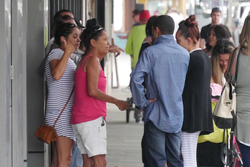 A woman and several others stand on a street.