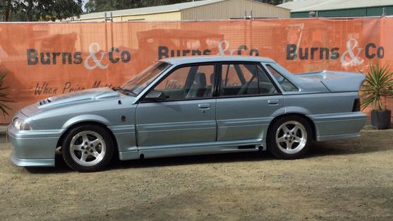 A boxy 1988 VL Walkinshaw Commodore in Panorama Silver parked at an auction lot.