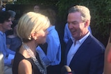 Julie Bishop and Christopher Pyne at a party in Adelaide, smiling and standing in front of a hedge.