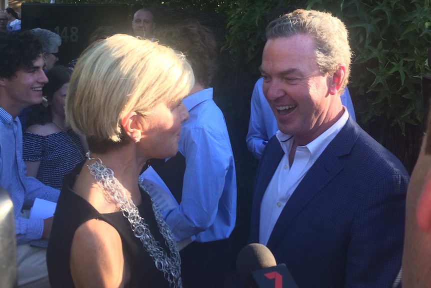 Julie Bishop and Christopher Pyne at a party in Adelaide, smiling and standing in front of a hedge.