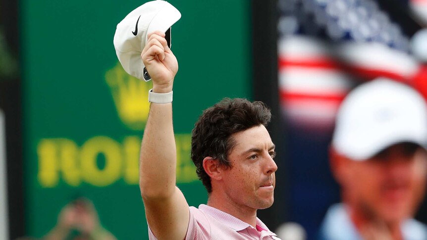 Rory McIlroy waves his hat above his head and purses his lips