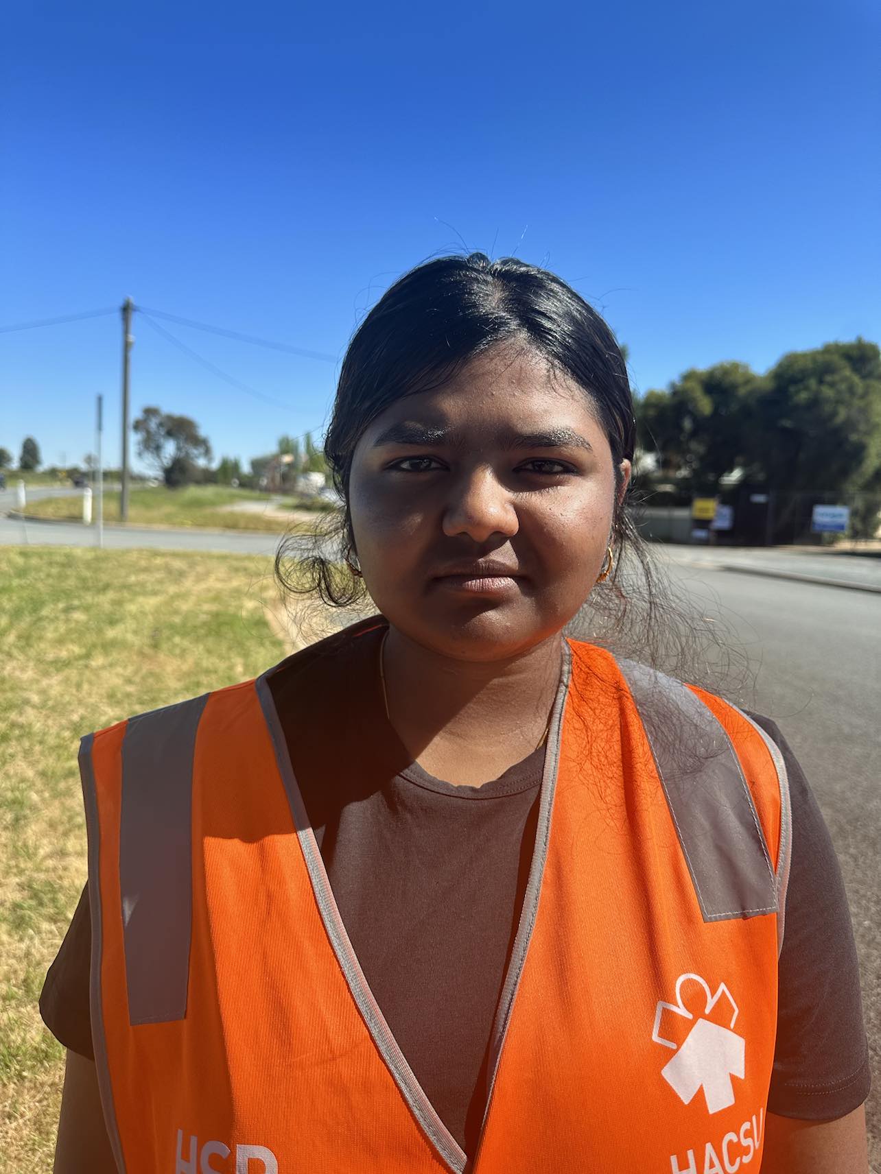 A women wearing orange high vis standing along a road