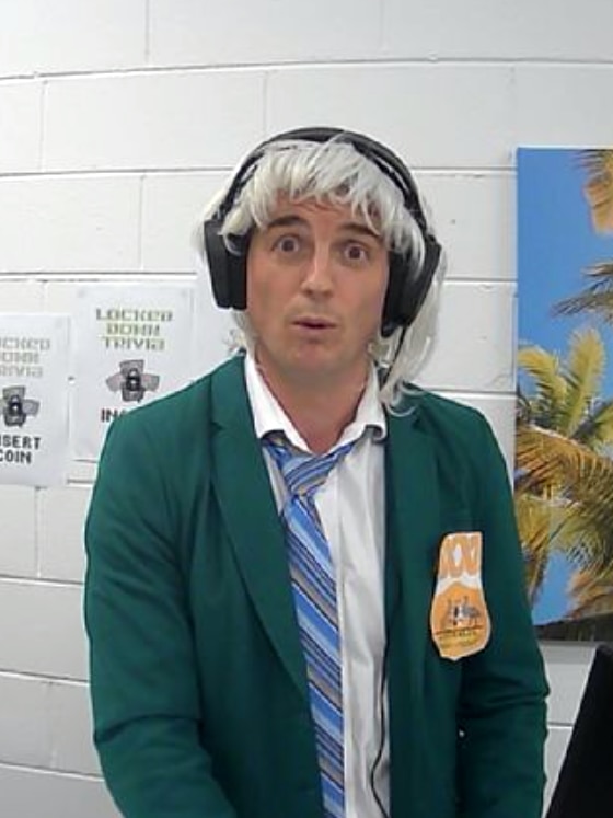 A man dressed up in a wig and a school blazer making a funny face at the camera