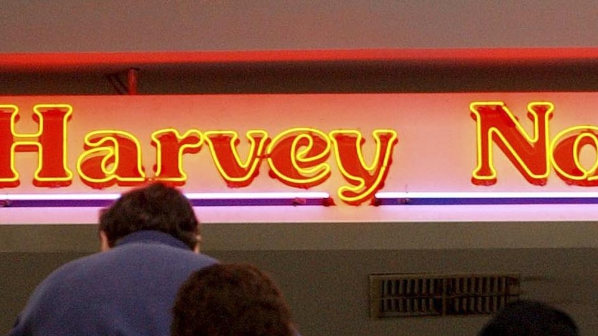 Shoppers walk up an escalator to a Harvey Norman store