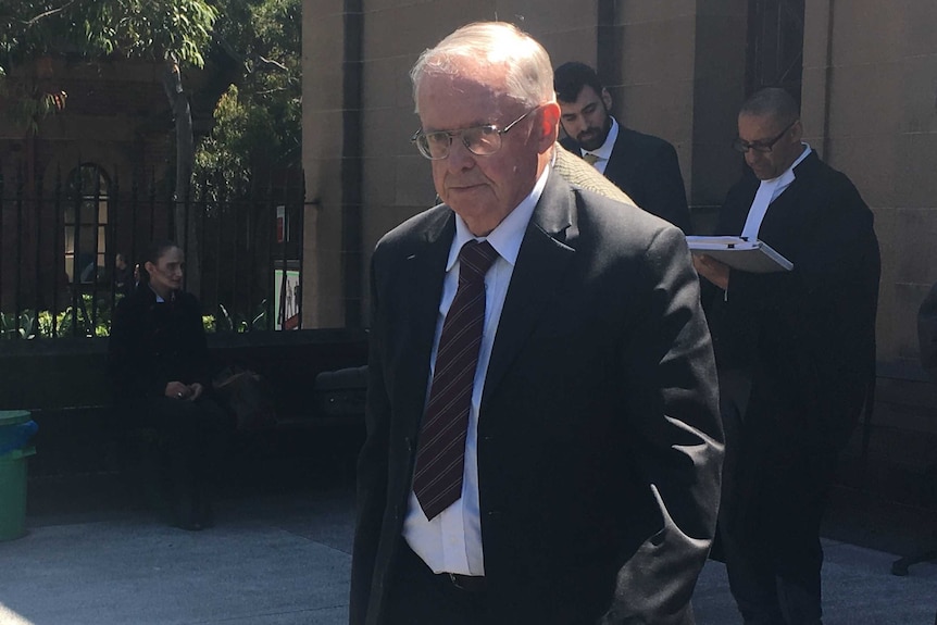 A bald Vincent Gerard Ryan leaves court in 2016, wearing a suit, tie, glasses, hands in his pocket.