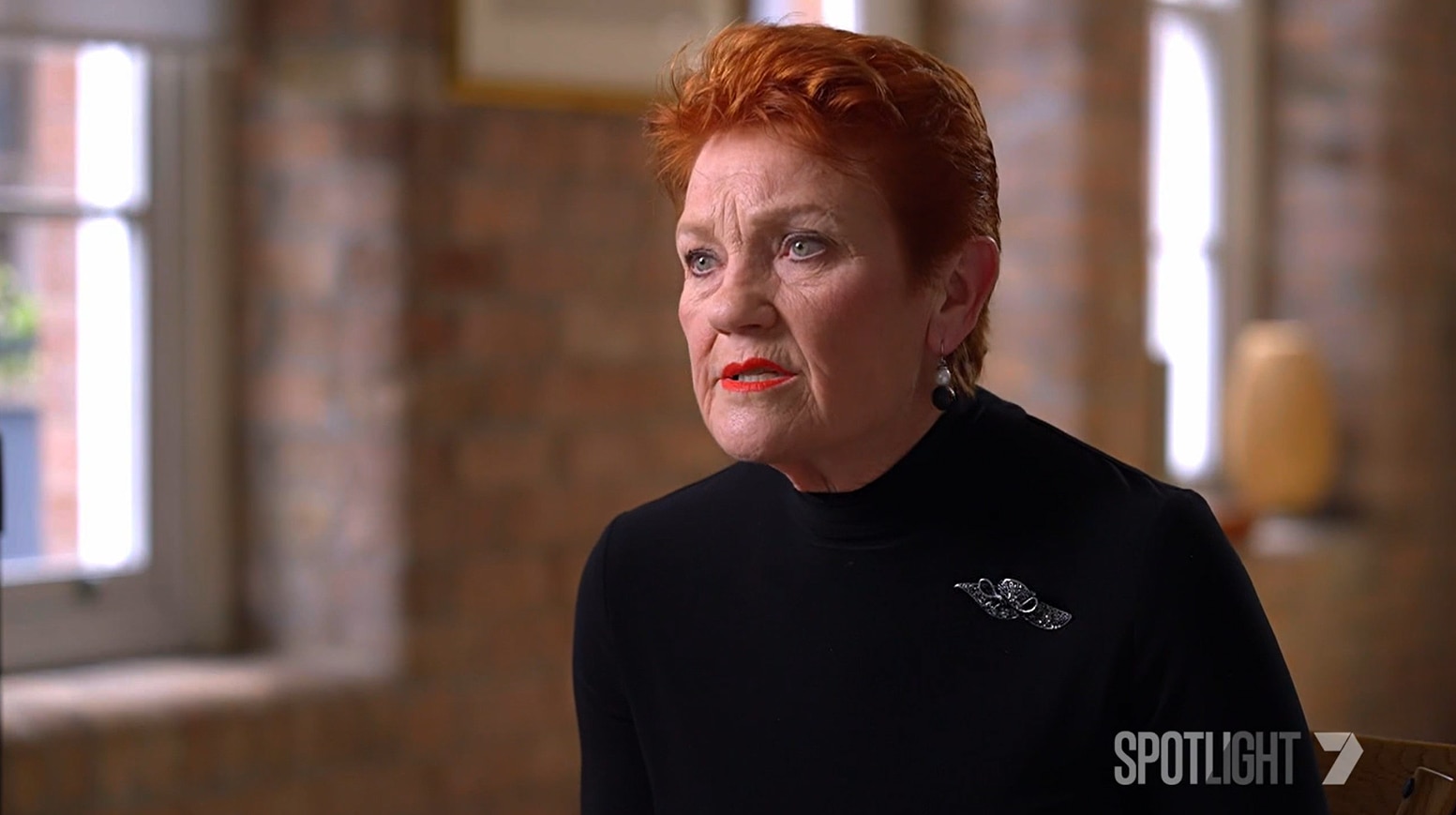 A woman with red hair wearing a black top.