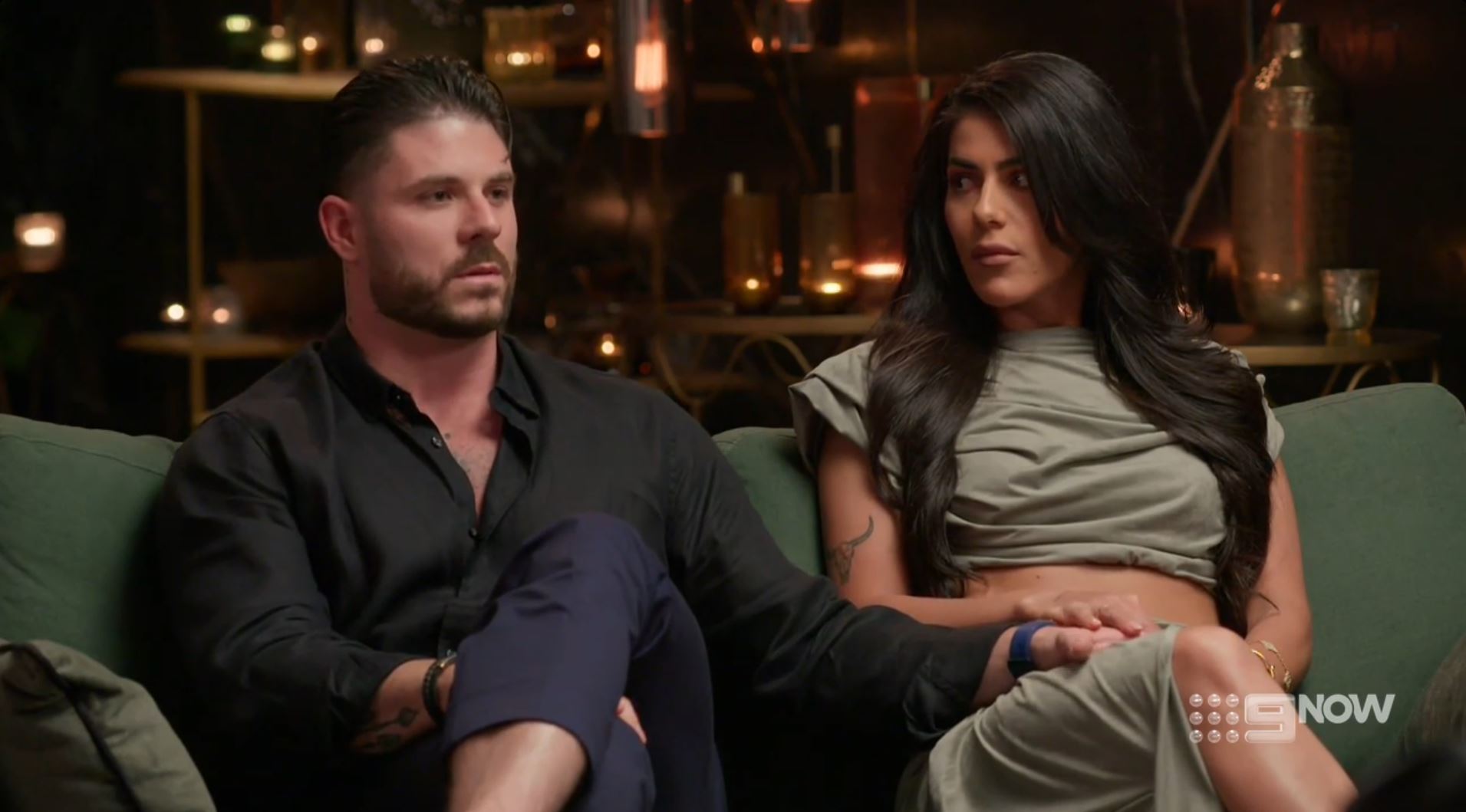 A man and a woman on a couch both looking upset. 