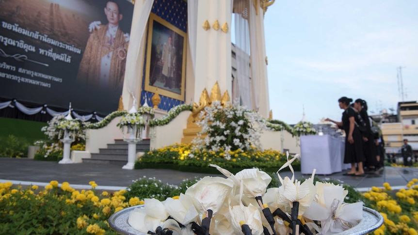 Thai mourners lay down sandalwood flowers in front of a giant portrait of late Thai King Bhumibol.