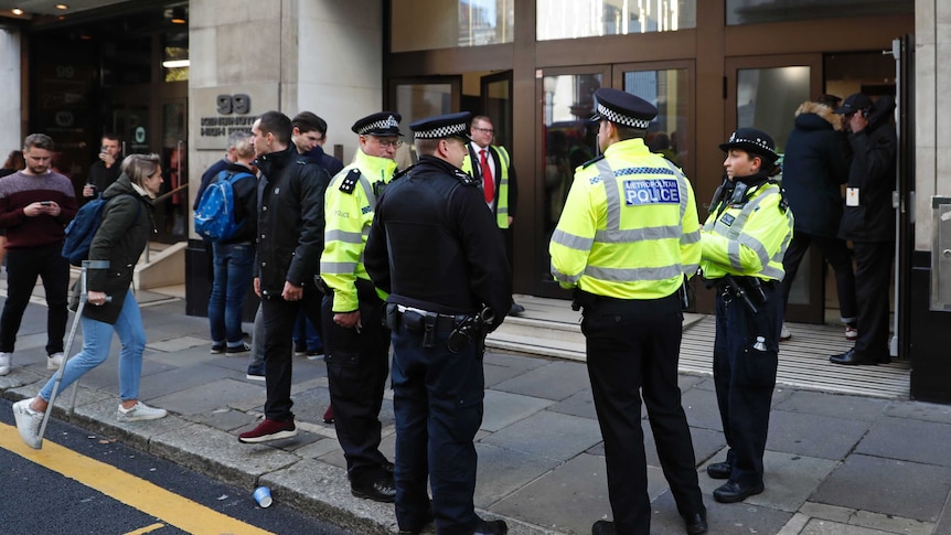 London police standing outside the Sony Music building with workers and bystanders outside