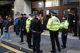 London police standing outside the Sony Music building with workers and bystanders outside
