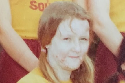 A young girl in a uniform sitting next to peers