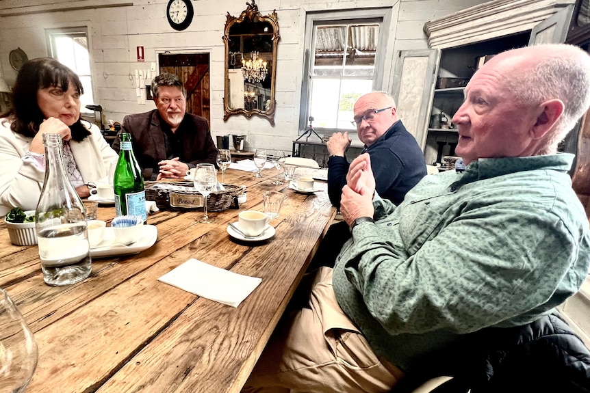 A crowd of men and women sitting around a table.