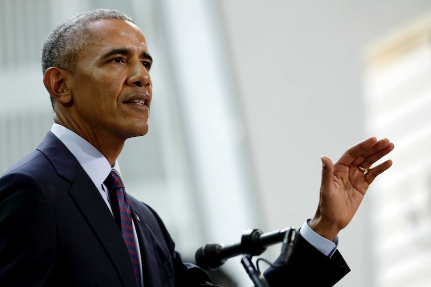 Barack Obama raises his hand as he speaks.