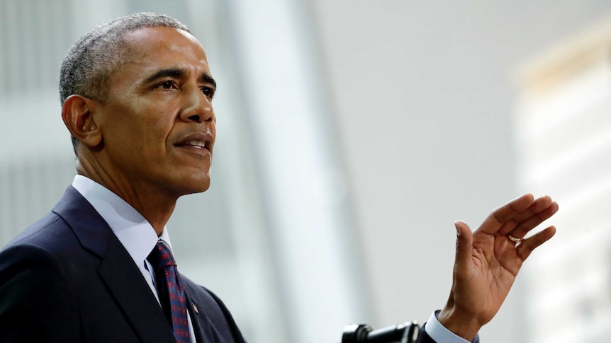 Barack Obama raises his hand as he speaks.