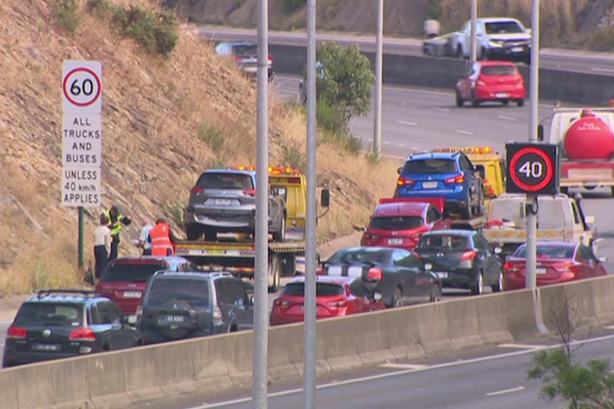 two cars mounted on tow trucks on a busy freeway