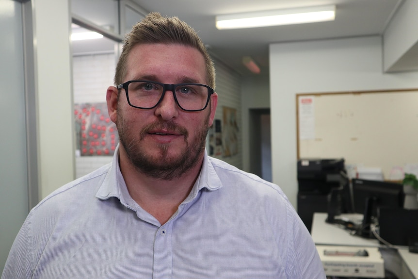 A man with a beard and moustache wearing glasses looks at camera