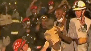 American police and firemen rescue two young children from the rubble in Haiti.
