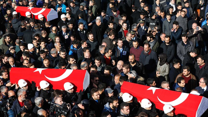 People carry the flag-draped coffins of police officers killed in Saturday's blasts in Istanbul.