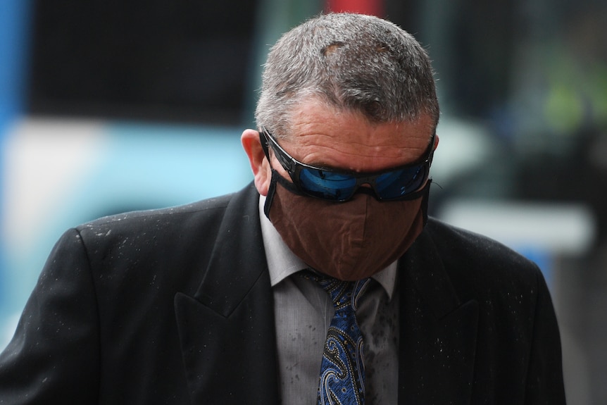 Mark Follington arrives at court wearing a mask