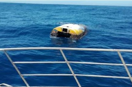 An overturned boat in the middle of the ocean.