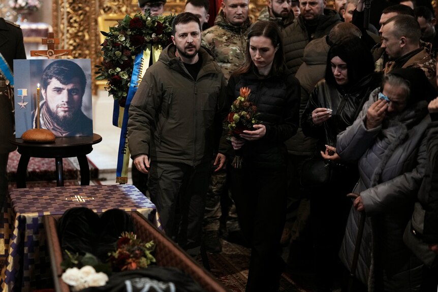 Zelenskyy and Finland's Prime Minister Sanna Marin stand near a portrait of a Ukraine fighter killed in battle.