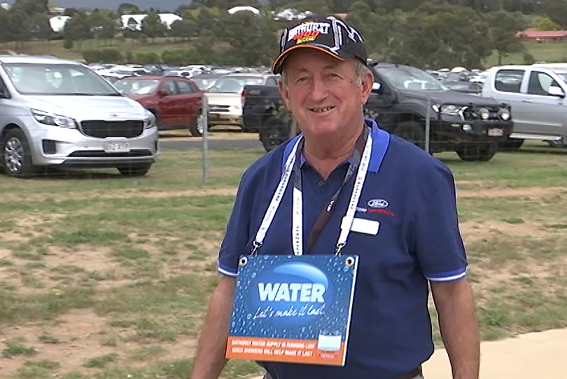 Bobby Bourke wearing a cap and a water conservation sign around his neck.