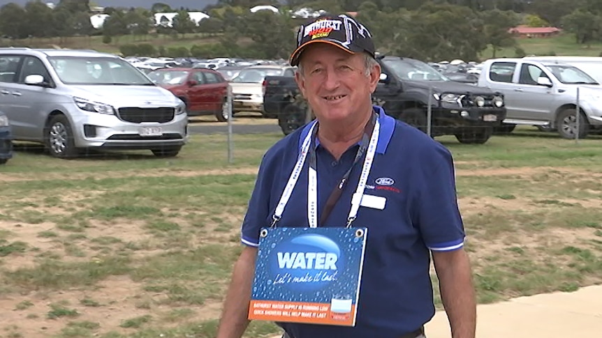 Bobby Bourke wearing a cap and a water conservation sign around his neck.