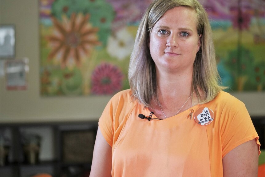 A blonde woman in an orange top.