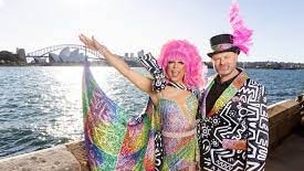 Drag queen Miss Ellanous standing on a boat with her arm around another person 