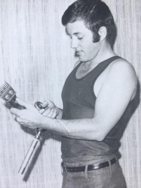 Photo of a young man sharpening a shearing tool.