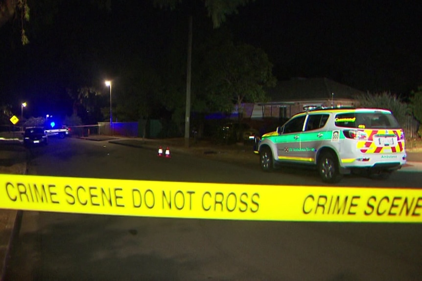 Crime scene tape across a street with a four-wheel drive ambulance and police car