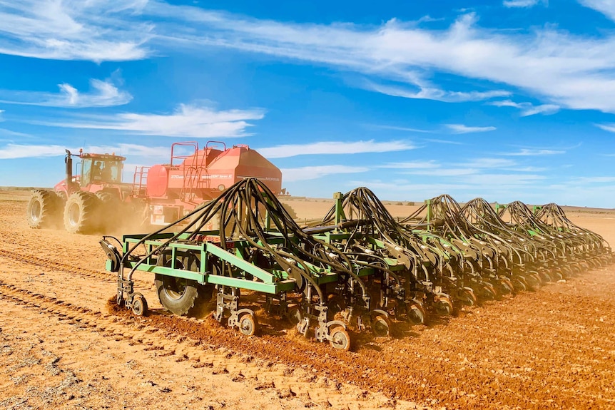 A tractor pulls a seeding rig across a paddock
