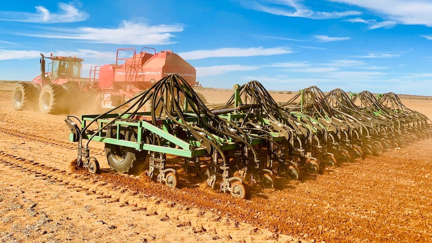 A tractor pulls a seeding rig across a paddock