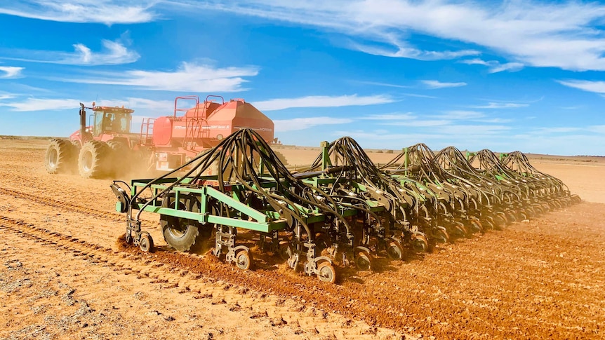 A tractor pulls a seeding rig across a paddock