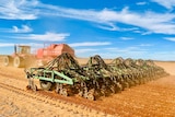 A tractor pulls a seeding rig across a paddock