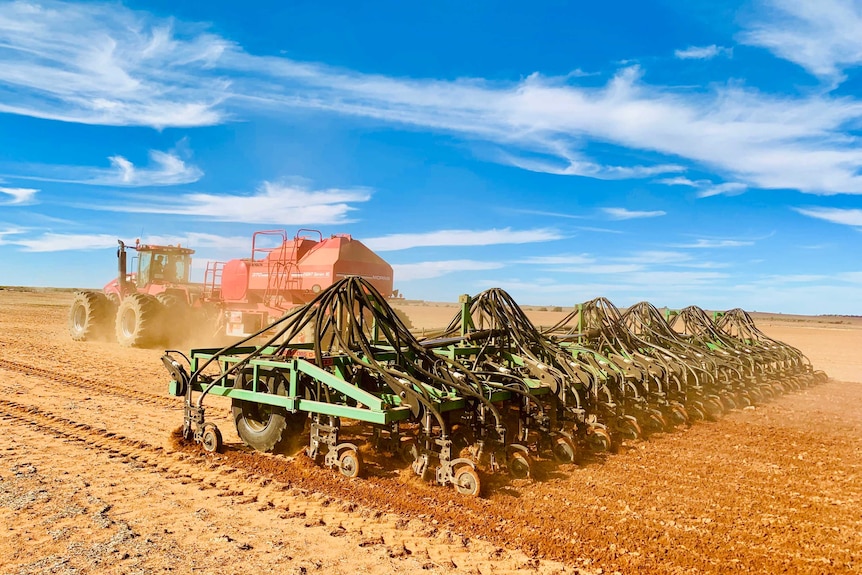 A tractor pulls a seeding rig across a paddock
