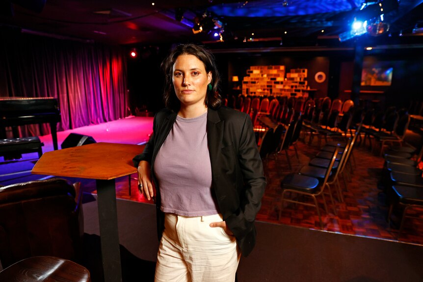 A woman stands inside a live music venue