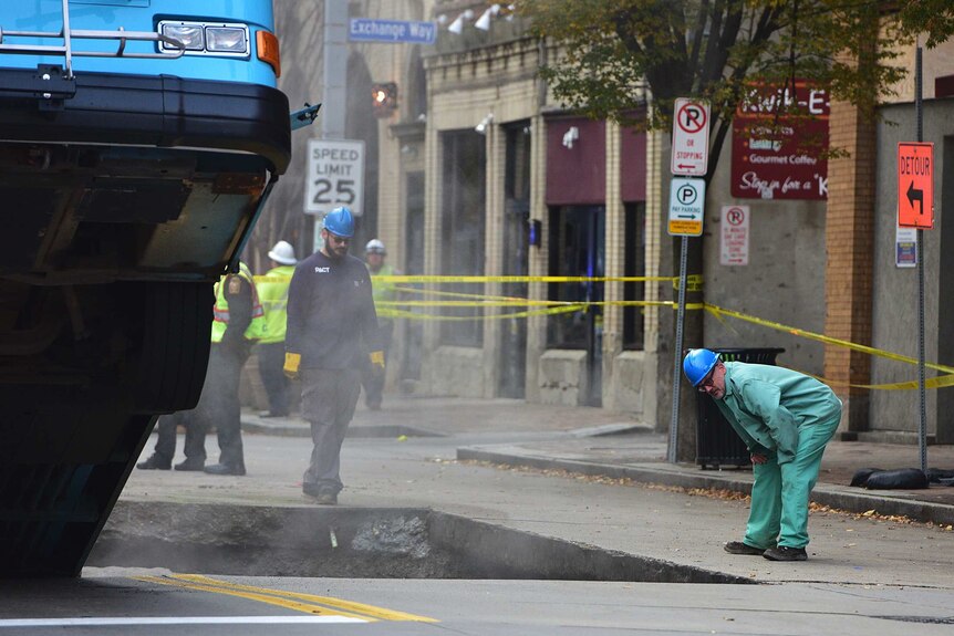 Crews work at the scene of a Port Authority bus that fell into a sinkhole