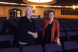 Two women standing in the downstairs section of a theatre looking towards the stage