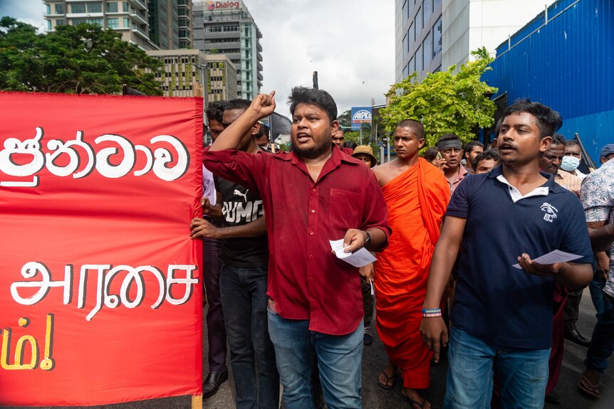 A man in a red shirt leading a protest.