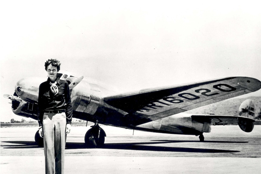 Amelia Earhart standing in front of her Lockheed Electra plane